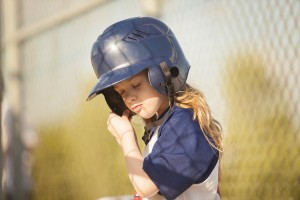 Girl Putting on a baseball Helmut